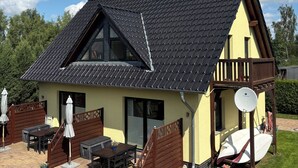 A house with a sloped roof, a balcony, a satellite dish, and outdoor furniture. - Holidays directly on the water with great additional services (Ziemitz)