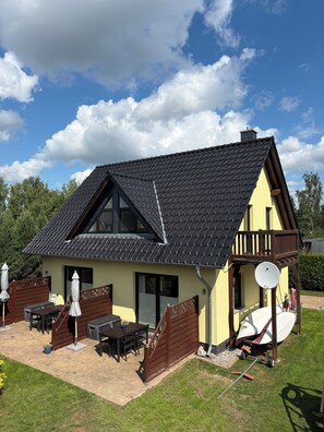 A house with a sloped roof, a balcony, a satellite dish, and outdoor furniture.