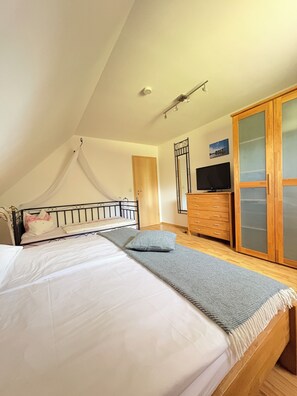 Un dormitorio con cama, cómoda, televisor y armario.
