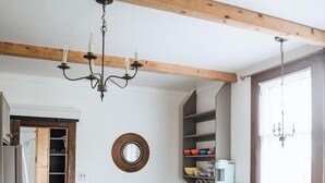 Une cuisine avec des poutres en bois, un lustre, un miroir rond et une fenêtre donnant sur un beau paysage.