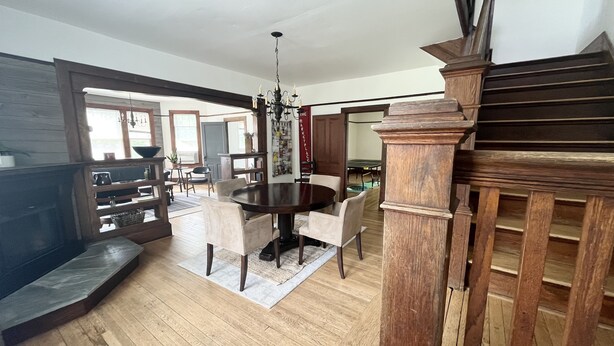 Un vaste salon doté d’un plancher en bois, un coin repas avec une table ronde et un escalier avec des rampes en bois.