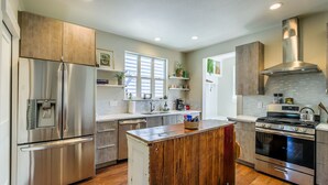 Une cuisine moderne dotée d’appareils électroménagers en acier inoxydable, de meubles en bois et d’un îlot central.
