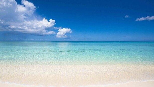 Een strand met helder turquoise water en een zandstrand.