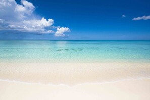 A beach with clear turquoise water and a sandy shore.