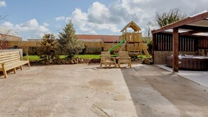 A backyard with a wooden play structure, a picnic table, and a covered seating area. - Neds Brae House (Ballymena)