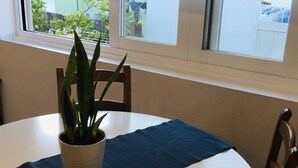 Une table de salle à manger ronde, recouverte d’une nappe blanche, agrémentée d’un set de table bleu foncé et d’une plante en pot.