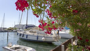 A marina with boats docked, a small rowboat, and a building in the background. - Holidays in MARINA in PORT CAMARGUE and 100m from the beach! (Le Grau-du-Roi)
