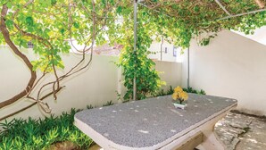 A stone bench with a small potted plant, surrounded by greenery and a pergola structure. - 2 bedroom amazing apartment in Razanac (Razanac)