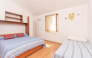 A bedroom with a bed, a wardrobe, a window with curtains, and a wall decoration. - 2 bedroom amazing apartment in Razanac (Razanac)