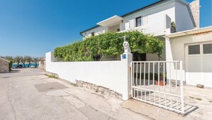 A modern two-story house with a white exterior, a gated entrance, and a number 21 sign. - 2 bedroom amazing apartment in Razanac (Razanac)