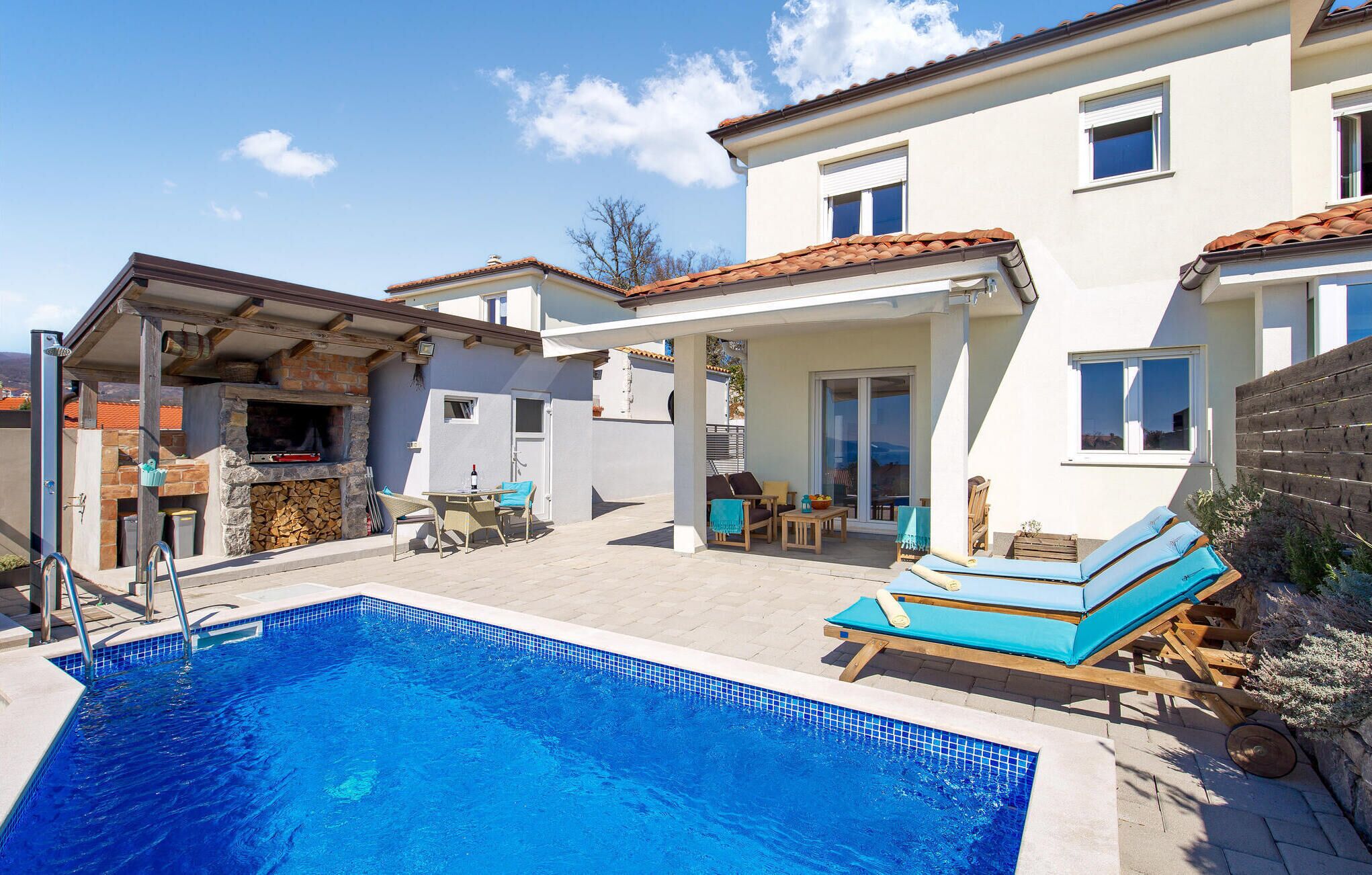 A swimming pool with lounge chairs and a barbecue area.