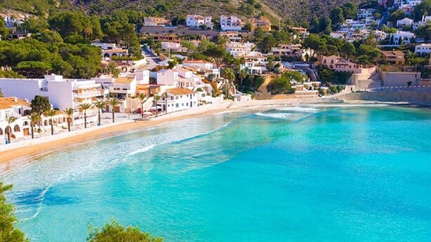 A coastal town with buildings along the beach, clear turquoise waters, and a hilly backdrop. - Traditional family villa, private pool and hillside views, 5 mins to Moraira. (Teulada)