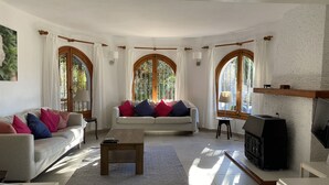 A cozy living room with a sofa, a coffee table, and a fireplace. - Traditional family villa, private pool and hillside views, 5 mins to Moraira. (Teulada)