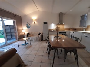 A compact living space with a dining area, kitchenette, and a sliding glass door leading to an outdoor area.