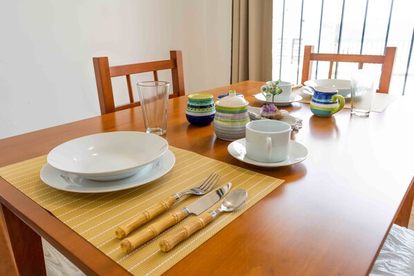 Una mesa de comedor dispuesta con platos, tazones, tazas y una jarrón.