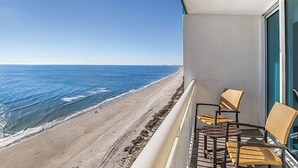 A balcony with wicker chairs overlooking a beach. - One-Bedroom Oceanfront Condo on Myrtle Beach (North Myrtle Beach)
