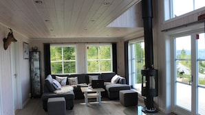 A modern living room with a sectional sofa, a fireplace, and large windows offering a view of the outdoors.