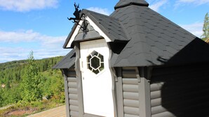 A small, dark-colored cabin with a white door and a decorative window.
