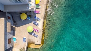 Une terrasse sur le toit avec une piscine, une eau turquoise cristalline et des chaises de plage avec des parasols.