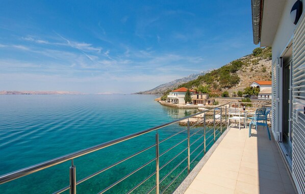 Enjoy the serene ocean views from your balcony with a clear view of the sea and surrounding rocky hillside.