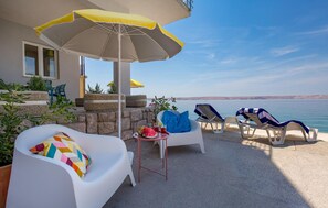 Relax on the seaside terrace with a clear view of the sea, surrounded by potted plants and a comfortable seating area.