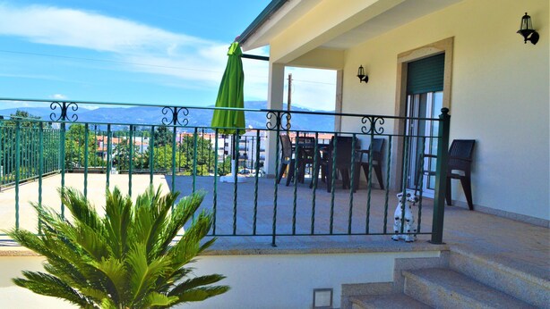 A balcony with a green umbrella, a dining table, and chairs. - Casa Límia (Ponte de Lima)