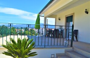A balcony with a green umbrella, a dining table, and chairs. - Casa Límia (Ponte de Lima)