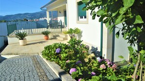 A white building with a balcony, potted plants, and flowers. - Casa Límia (Ponte de Lima)