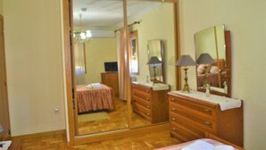 A bedroom with a large mirror, wooden dresser, and a bed with a pink bedspread. - Casa Límia (Ponte de Lima)