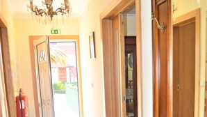 A hallway with a wooden floor, a chandelier, and a fire extinguisher. - Casa Límia (Ponte de Lima)