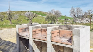 A concrete structure with benches, set against a backdrop of a green hillside and trees. - Lovely home in Ragusa with outdoor swimming pool (Ragusa)