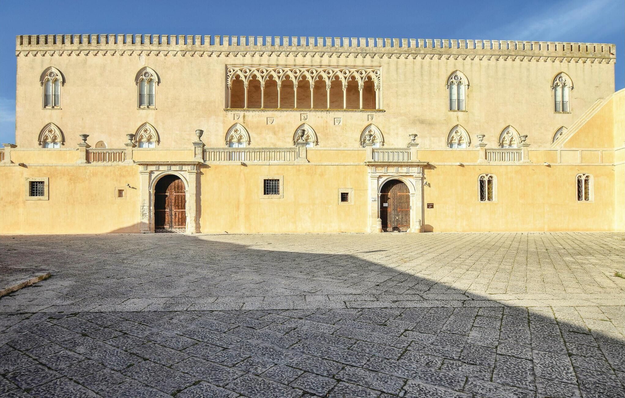 A historic building with a symmetrical facade, arched windows, and a central courtyard with a paved floor.