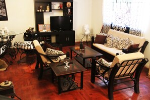 Una sala de estar con sofá, sillones, una mesa de centro y televisor.