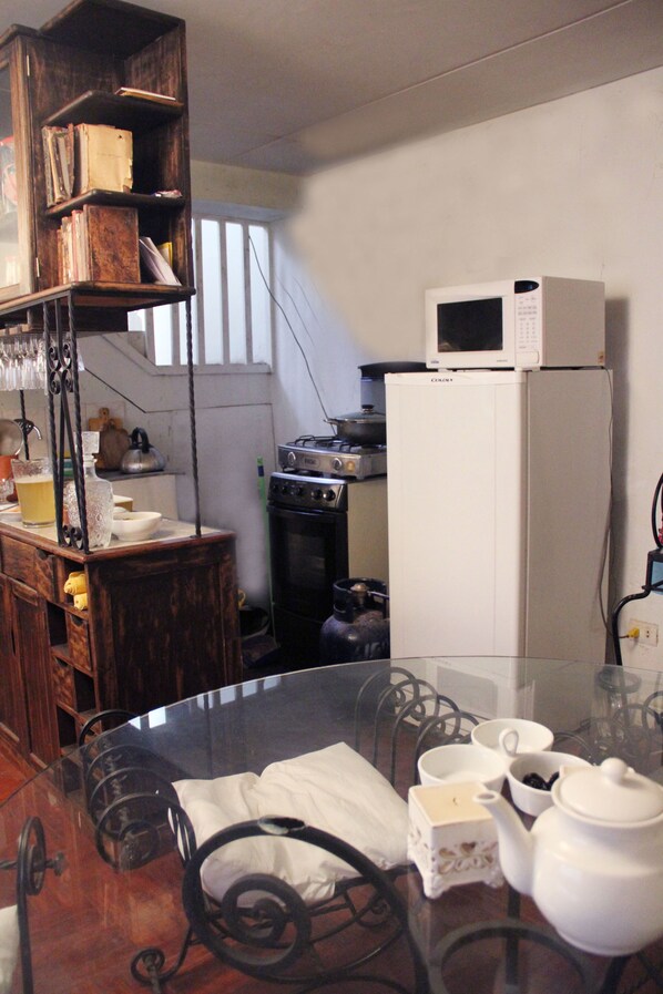 Una cocina con una mesa de vidrio, un refrigerador blanco y estantes de madera.