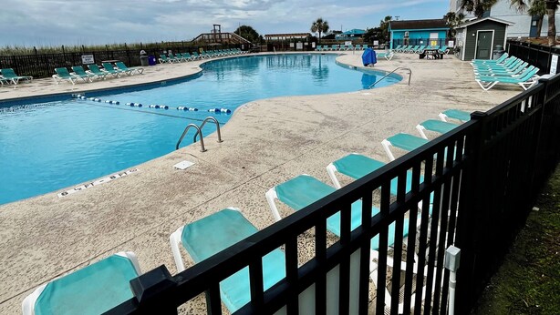 A pool area with multiple lounge chairs and a clear sky. - S. Myrtle Beach Resort 135 steps to sand  (Myrtle Beach)