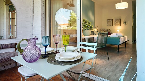 A dining area with a table set for two, a bench, and a view of the adjacent room. - Cosy app, balcony, S. Peter's view, parking (Roma)