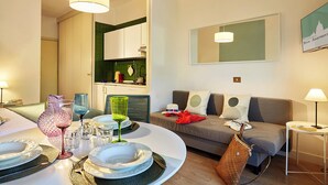 A modern living room with a dining area, a sofa set, and a kitchen visible in the background. - Cosy app, balcony, S. Peter's view, parking (Roma)