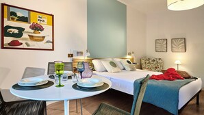 A hotel room with a bed, bedside table, chairs, and a dining area with a table and chairs. - Cosy app, balcony, S. Peter's view, parking (Roma)