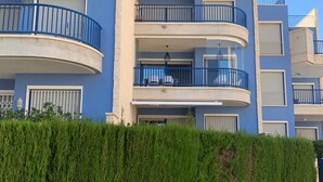 A multi-story residential building with balconies, a paved walkway, and a well-maintained hedge. - Modern 2 slaapkamerappt met zwembad-jacuzzi, terras 1 sts lijn in afgesl. res. (Orhiuela-Costa)