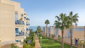 A resort with multiple-story buildings, a well-maintained garden with palm trees, and a clear view of the sea. - Modern 2 slaapkamerappt met zwembad-jacuzzi, terras 1 sts lijn in afgesl. res. (Orhiuela-Costa)