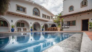 Una piscina con un área de patio, una mesa de comedor y sillas.