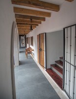 Un pasillo con vigas de madera, una escalera y un banco.