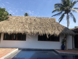 Una casa con techo de paja y piscina.