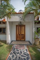 A building entrance with a double wooden door, a tiled roof, and a welcome mat.