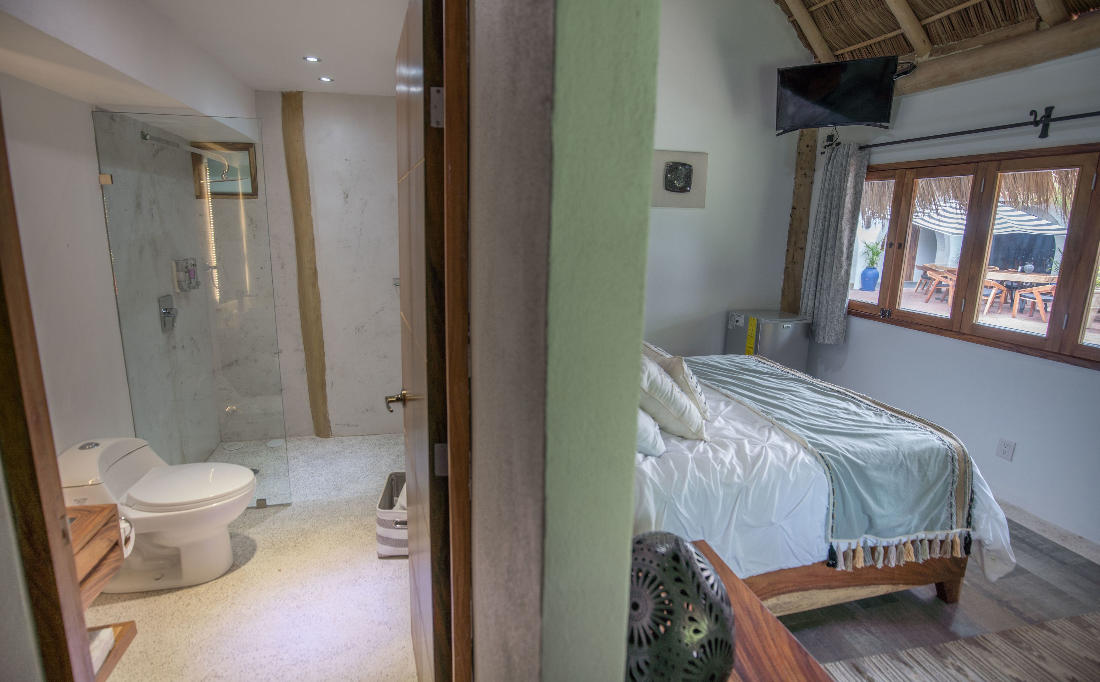 Un dormitorio con cama, televisión y baño completo.