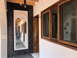 A hallway with a large mirror, a wooden door, and a window with curtains.