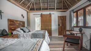 A bedroom with a wooden headboard, a bed with patterned bedding, a desk with a chair, and a large window with a view. - A Villa San Juan Bed & Breakfast (Nuevo Nayarit)