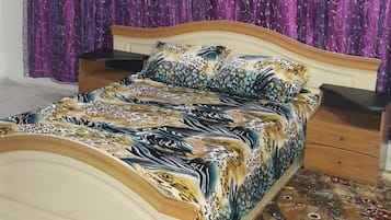 Ein Schlafzimmer mit einem Bett, zwei Nachttischen und violetten Vorhängen.