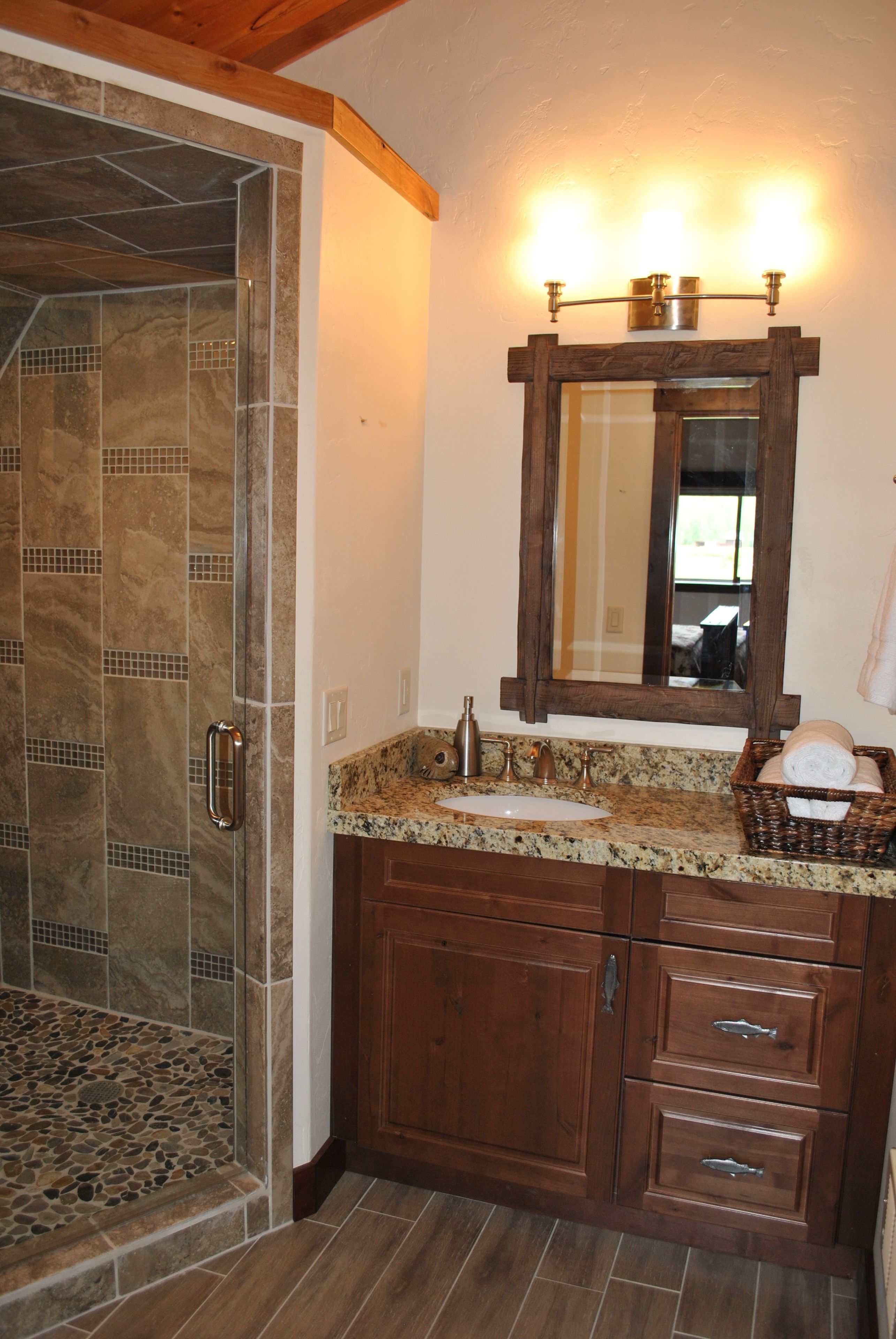 A bathroom with a shower, vanity, and a large mirror.