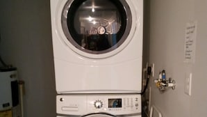 A stacked washer and dryer unit in a laundry room. - Orchard Lane at Round Lake. (Manitou Beach)